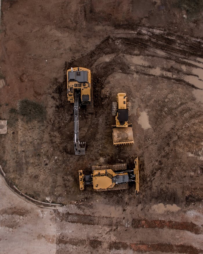 get-in-touch An aerial shot of heavy machinery at a construction site, including excavators and road rollers.