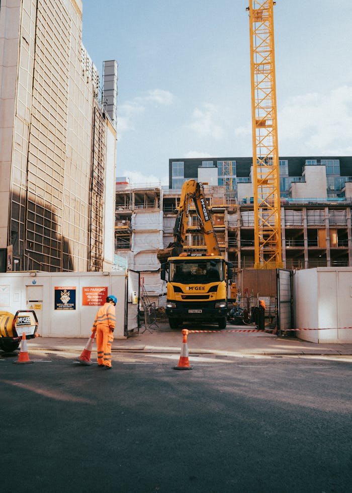 about-us City construction site featuring worker, machinery, and urban surroundings in progress under bright daylight.