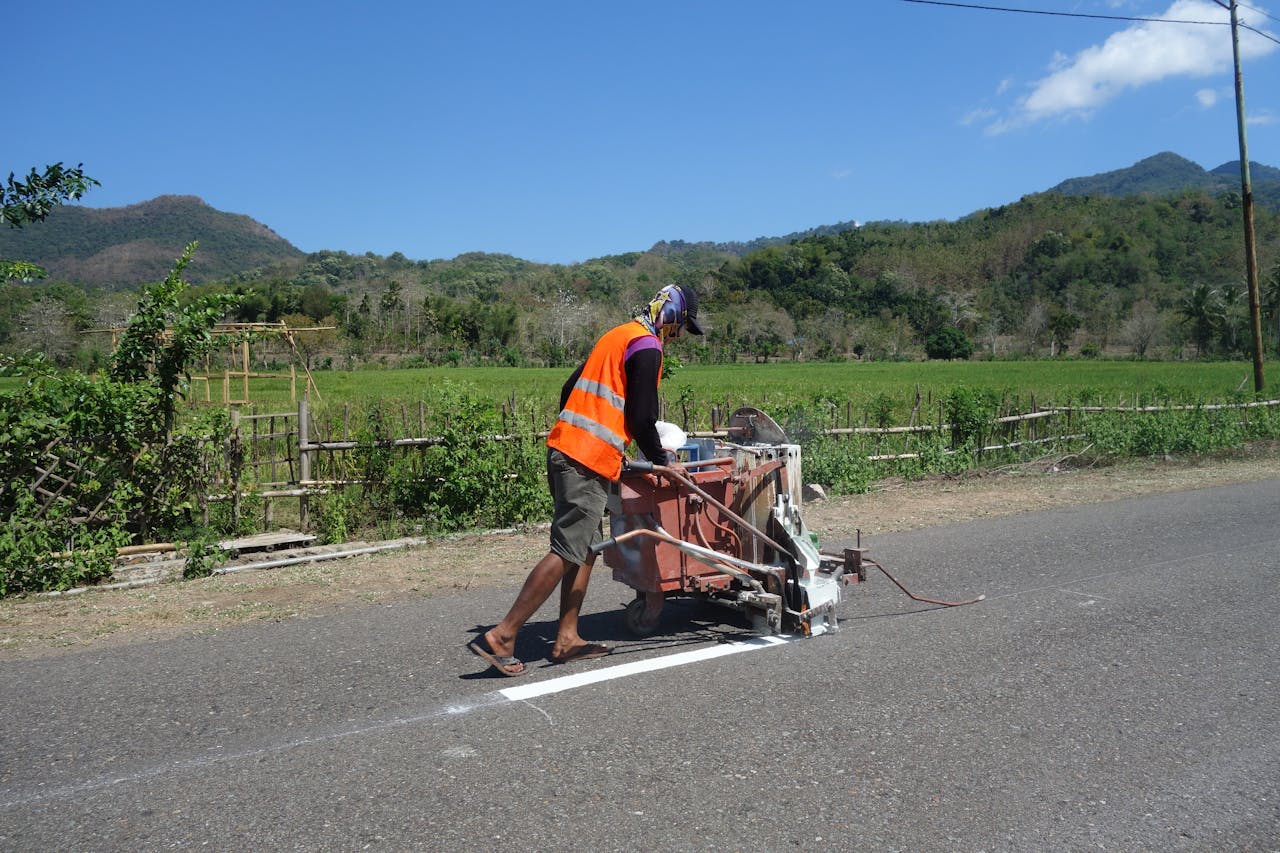 Crafting Captivating Headlines: Your awesome post title goes here A construction worker uses machinery to paint road lines in a rural area on a sunny day.