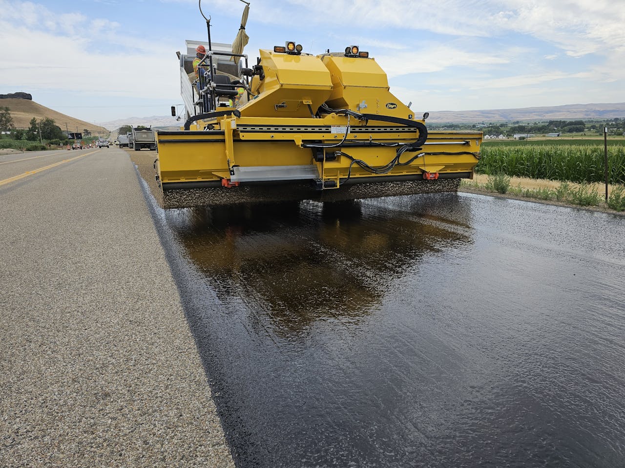 who-we-are Yellow road construction machine applying asphalt on a rural road in Marsing, Idaho.