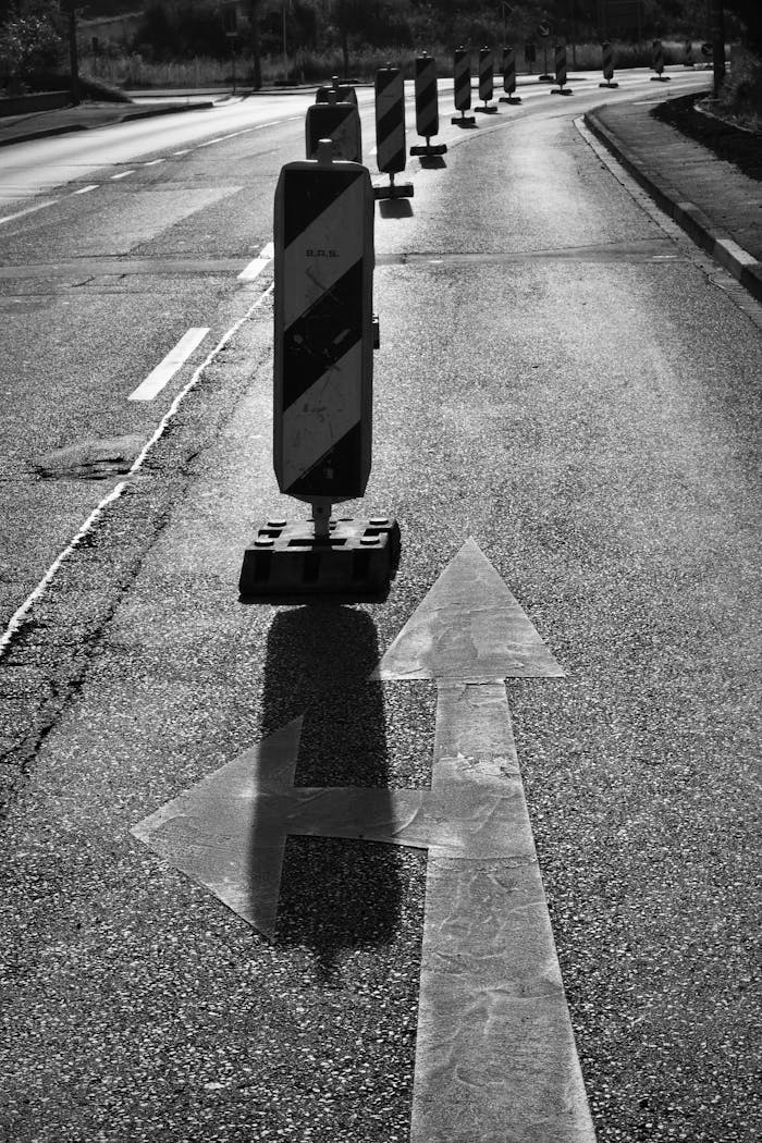Mastering the First Impression: Your intriguing post title goes here Black and white image of a road with traffic barrier and directional arrows, indicating road construction.